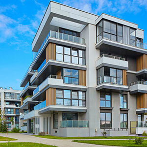 A modern apartment complex with multiple buildings, balconies, and large windows on a sunny day.